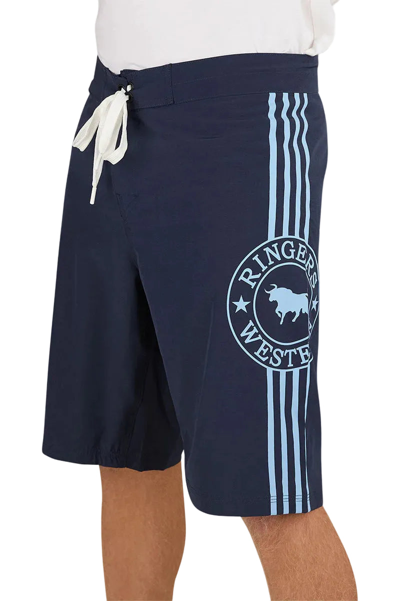 A person wears Ringers Western Mens Southern Cross Swim Shorts (124085RW) NSW—navy with light blue stripes, a circular Ringers Western bull logo on the left leg, white drawstring, and made from recycled polyester.