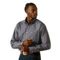 A man wearing a navy Ariat Men's Wrinkle Free Dale L/S Shirt (10062195) with a small white geometric pattern, paired with a brown western belt and blue jeans, against a solid white background.