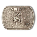 The Ariat Rectangle Vintage Saddle Bronc Buckle (A37053) in aged silver features ornate scrolling, "ARIAT" at the top, a cowboy riding a bronc in the center, and the Ariat logo inside a shield at the lower right.