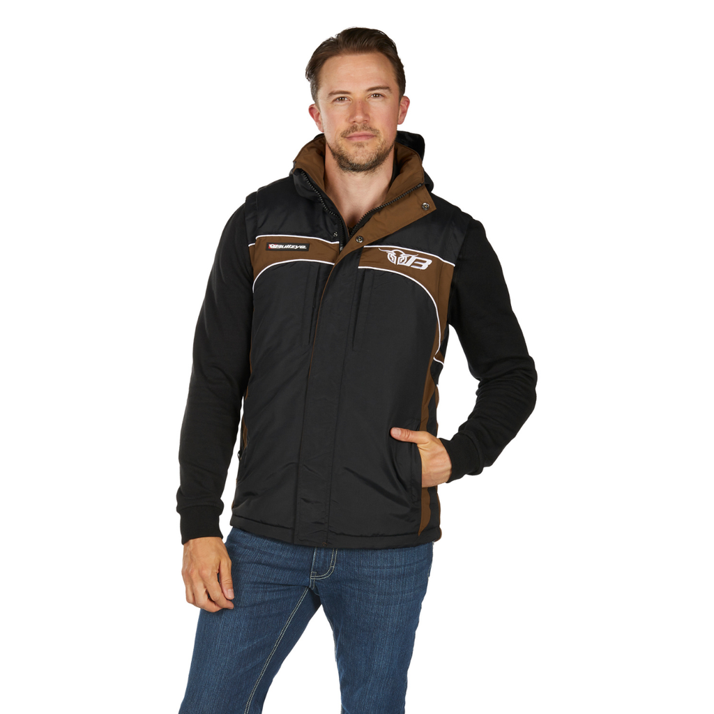 A man wears the Bullzye Mens Bazooka Vest (B6W1604039) in Black/Dark Tan with white accents and blue jeans, standing facing forward with one hand in his pocket and the other relaxed by his side.