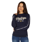 A woman with long brown hair wears a Bullzye Womens Ellie Crew Jumper (B6W2539532) in navy and blue jeans as she poses against a plain white background.