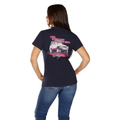 A woman faces away from the camera in a Bullzye Womens Vibes S/S Tee (B6W2503527) Navy, featuring a pink and white car graphic with “GIRL WEEKEND VIBES” and “Bailey’s,” styled with blue jeans.