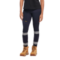 A woman from the waist down wearing navy blue CAT Women's Taped Work Stretch Leggings (1810096) with hi vis taping on the lower legs, paired with a black tee and honey coloured work boots, on a white background.