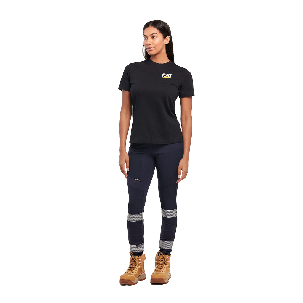 A woman wearing navy blue CAT Women's Taped Work Stretch Leggings (1810096) with hi vis taping on the lower legs, paired with a black CAT tee and honey coloured work boots, on a white background.