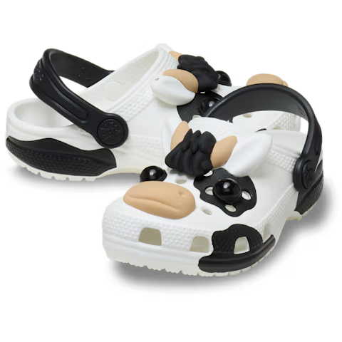 The Crocs Toddlers Classic IAM Cow Clogs (212902-100) in white feature a fun black and white cow design with 3D face, ears, snout, and spots—perfect for kids who love playful footwear.