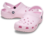 The Crocs Unisex Classic Clogs (10001-6ZW) Pink Milk feature ventilation holes, adjustable heel straps, and cushioned comfort. These water-friendly Crocs are shown in light pink on a white background.