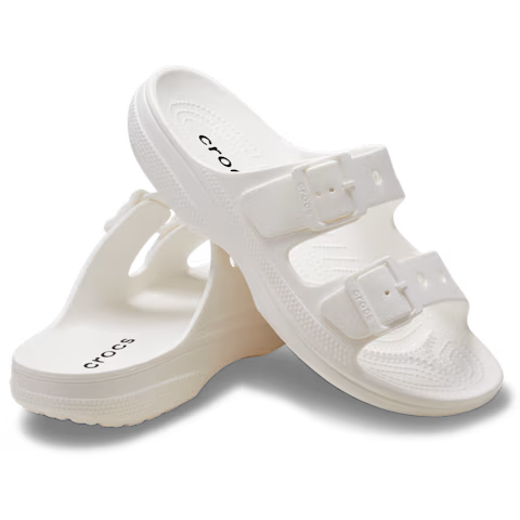 A pair of Crocs Womens Saturday Sandals (213586-100) in white, each with two adjustable straps—one sandal upright, the other leaning against it on a plain background—crafted for signature Crocs comfort.