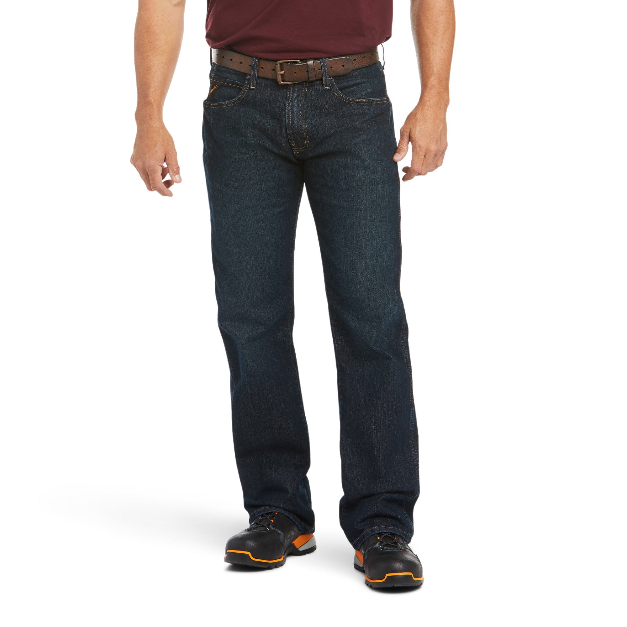 A man, face not visible, stands against a white background wearing a maroon shirt, brown belt, black work boots, and Ariat Rebar M5 Jeans (10016223) Blackstone by Ariat.