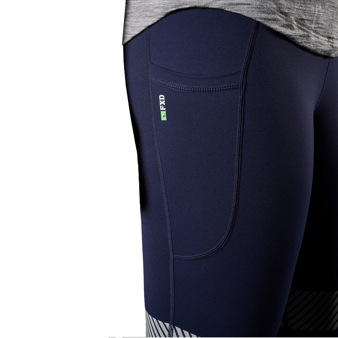 A close up view of the pocket of a pair of navy FXD Women's Taped Work Leggings (WP-9WT) paired with a grey tee on a white background.