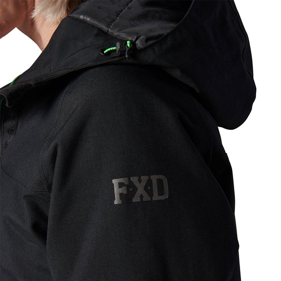 Close-up of a woman modelling a black hooded FXD Women's WO-1W Insulated Waterproof Jacket (FX12407001) with an FXD logo on the upper sleeve and small bright green drawcord accents near the hood.
