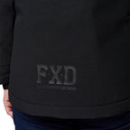 Close-up of a woman modelling a black hooded FXD Women's WO-1W Insulated Waterproof Jacket (FX12407001), showing an FXD 'Function by Design' logo on the front and dark blue pants below.