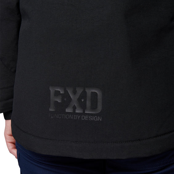 Close-up of a woman modelling a black hooded FXD Women's WO-1W Insulated Waterproof Jacket (FX12407001), showing an FXD 'Function by Design' logo on the front and dark blue pants below.