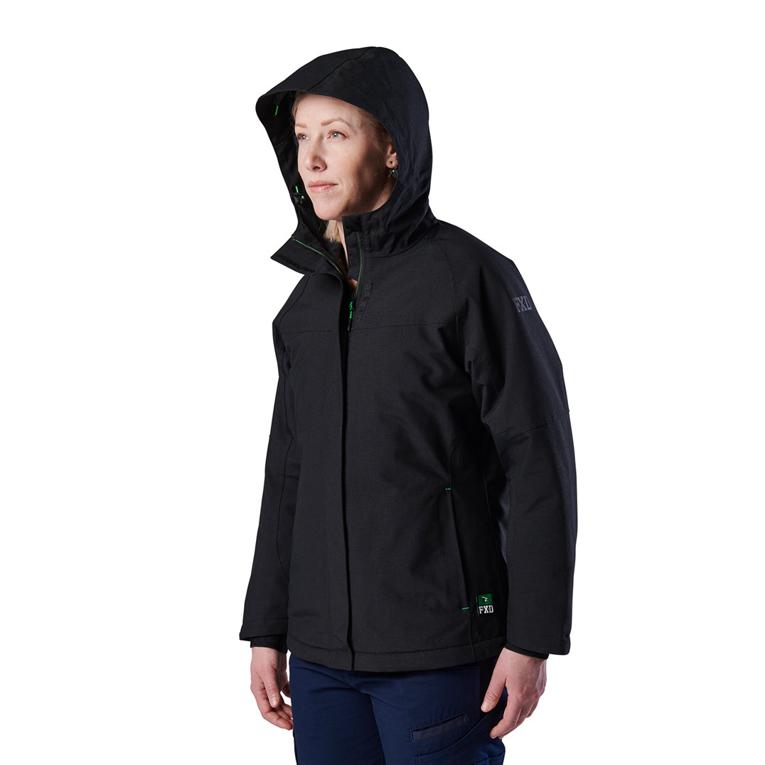 A woman modelling a black hooded FXD Women's WO-1W Insulated Waterproof Jacket (FX12407001) with green zipper accents and a small green logo near the hem, shown in profile against a plain white background.