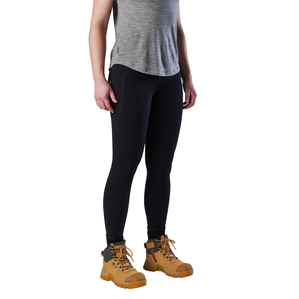 A 3-4 view of a woman modelling a black pair of FXD Women's Work Leggings (WP-9W) paired with a grey tee and wheat coloured work boots against a white background.