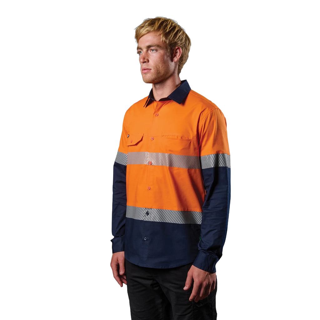 A 3-4 left view of a man wearing an orange and navy FXD Men's LSH-4T Vented Tech Hi-Vis Long Sleeve Work Shirt (FX02504010) with hi vis tape and a pair of black work pants on a white background.