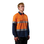 A 3-4 right view of a man wearing an orange and navy FXD Men's LSH-4T Vented Tech Hi-Vis Long Sleeve Work Shirt (FX02504010) with hi vis tape and a pair of black work pants on a white background.