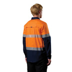 A 3-4 back right view of a man wearing an orange and navy FXD Men's LSH-4T Vented Tech Hi-Vis Long Sleeve Work Shirt (FX02504010) with hi vis tape and a pair of black work pants on a white background.