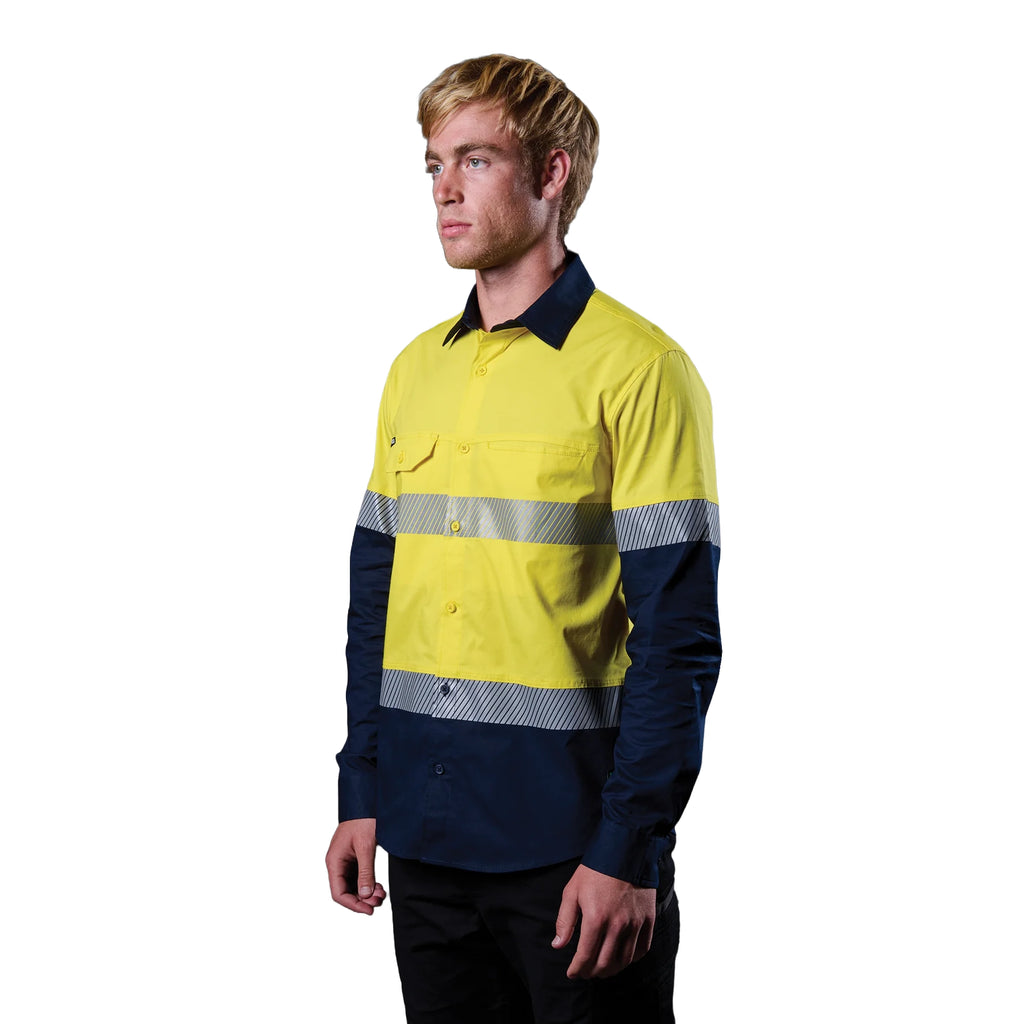 A 3-4 left view of a man wearing a yellow and navy FXD Men's LSH-4T Vented Tech Hi-Vis Long Sleeve Work Shirt (FX02504010) with hi vis tape and a pair of black work pants on a white background.