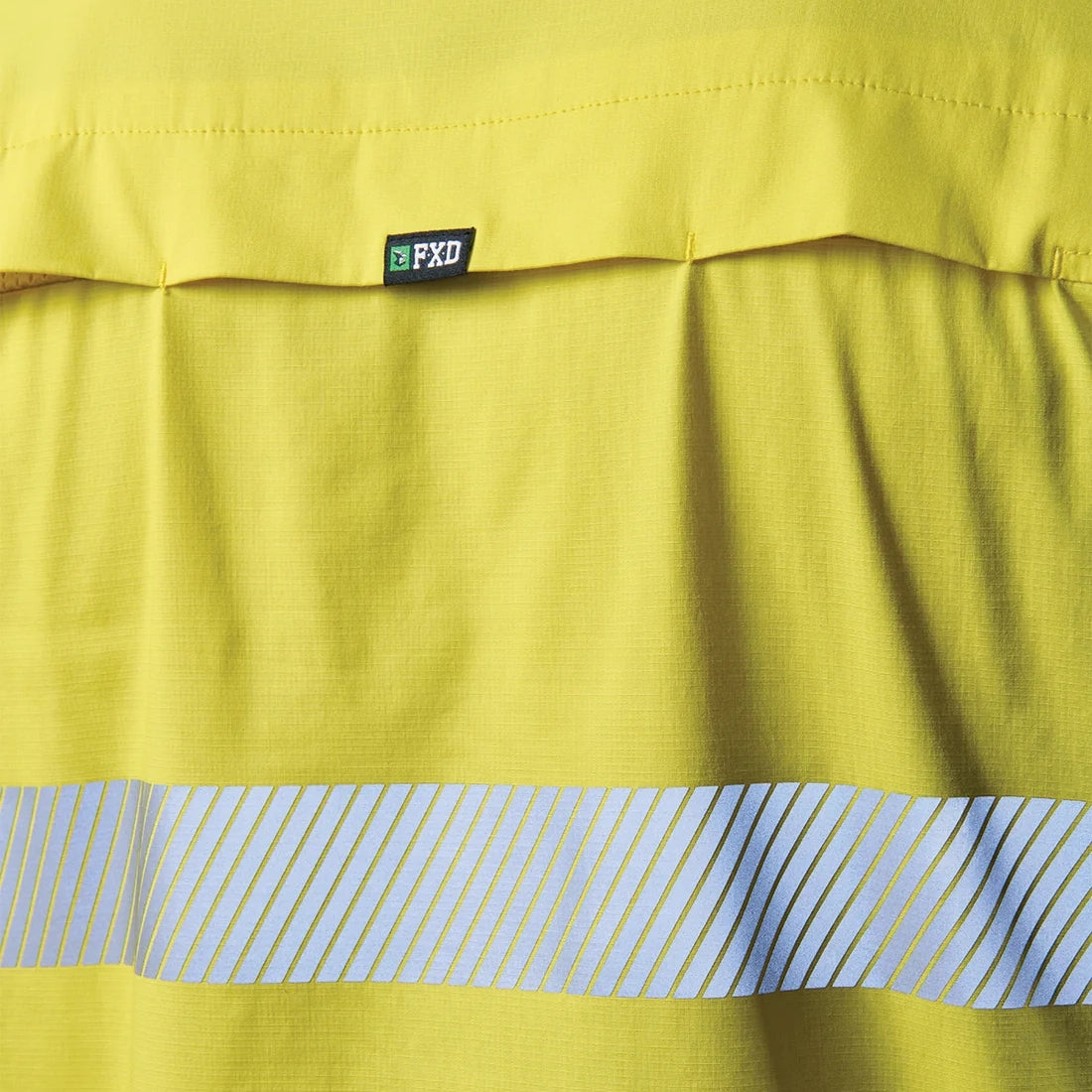 Close up detail of a yellow and navy FXD Men's LSH-4T Vented Tech Hi-Vis Long Sleeve Work Shirt (FX02504010) with hi vis tape on a white background.