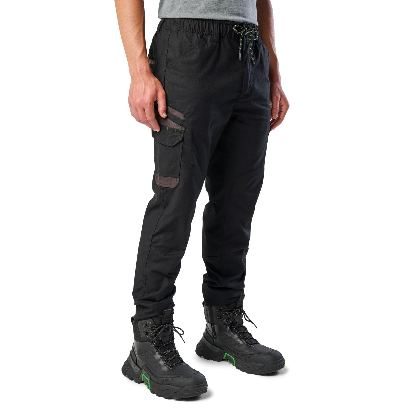 A man wearing black cargo style FXD WP-12C Elastic Waist Stretch Ripstop Cuffed Work Pants (FX02506027) with a drawstring waist and black work boots, shown from the waist down on a plain white studio background, 3-4 front view.