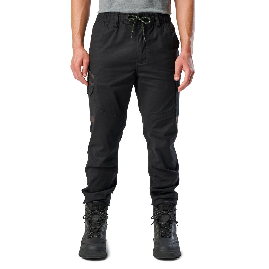 A man wearing black cargo style FXD WP-12C Elastic Waist Stretch Ripstop Cuffed Work Pants (FX02506027) with a drawstring waist and black work boots, shown from the waist down on a plain white studio background.