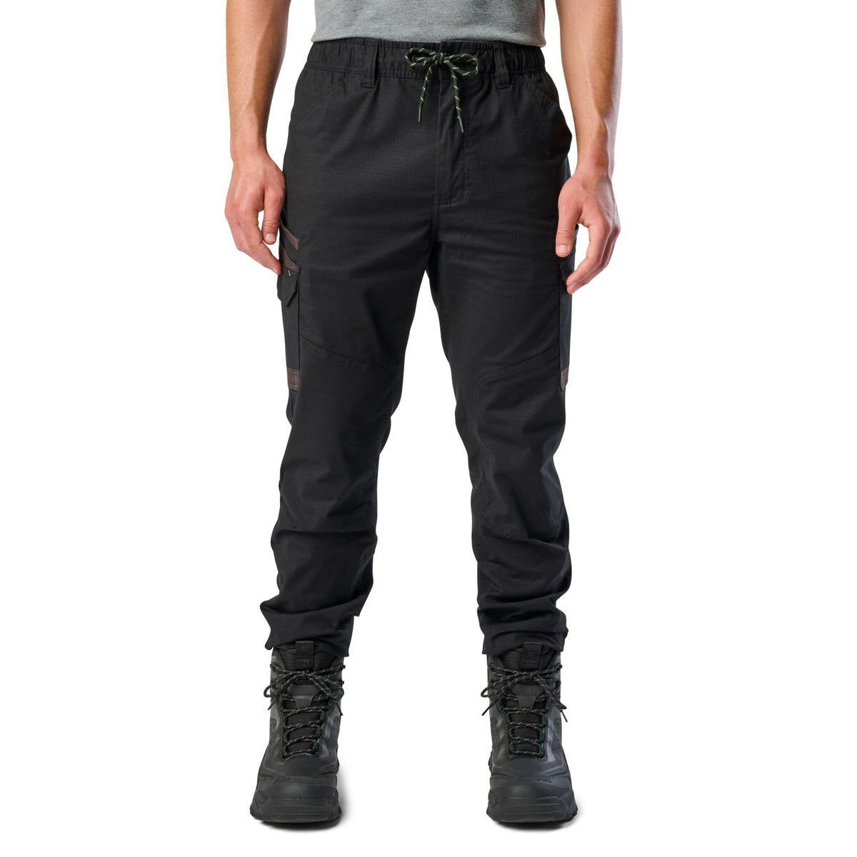 A man wearing black cargo style FXD WP-12C Elastic Waist Stretch Ripstop Cuffed Work Pants (FX02506027) with a drawstring waist and black work boots, shown from the waist down on a plain white studio background.