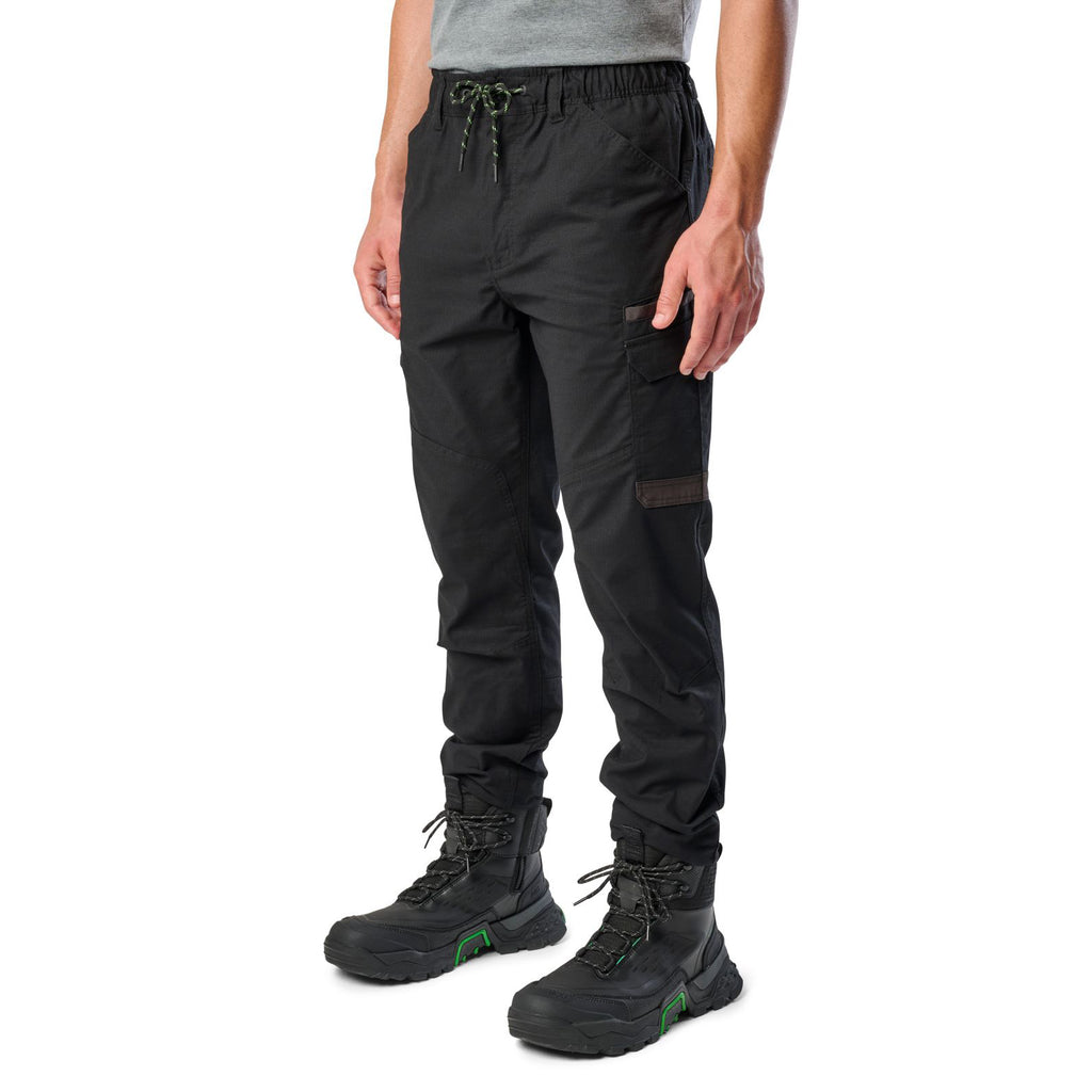 A man wearing black cargo style FXD WP-12C Elastic Waist Stretch Ripstop Cuffed Work Pants (FX02506027) with a drawstring waist and black work boots, shown from the waist down on a plain white studio background 3-4 front view.