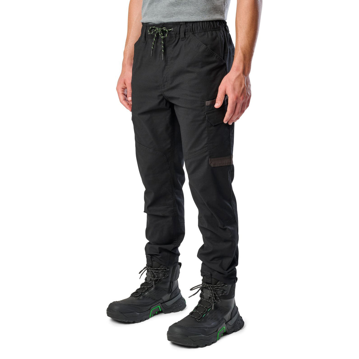 A man wearing black cargo style FXD WP-12C Elastic Waist Stretch Ripstop Cuffed Work Pants (FX02506027) with a drawstring waist and black work boots, shown from the waist down on a plain white studio background 3-4 front view.