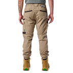 A back view of a man wearing khaki cargo style FXD WP-12C Elastic Waist Stretch Ripstop Cuffed Work Pants (FX02506027) with a drawstring waist and wheat work boots, shown from the waist down on a plain white studio background.