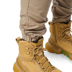 Cuff detail of a pair of khaki cargo style FXD WP-12C Elastic Waist Stretch Ripstop Cuffed Work Pants (FX02506027) and wheat work boots, on a plain white studio background.