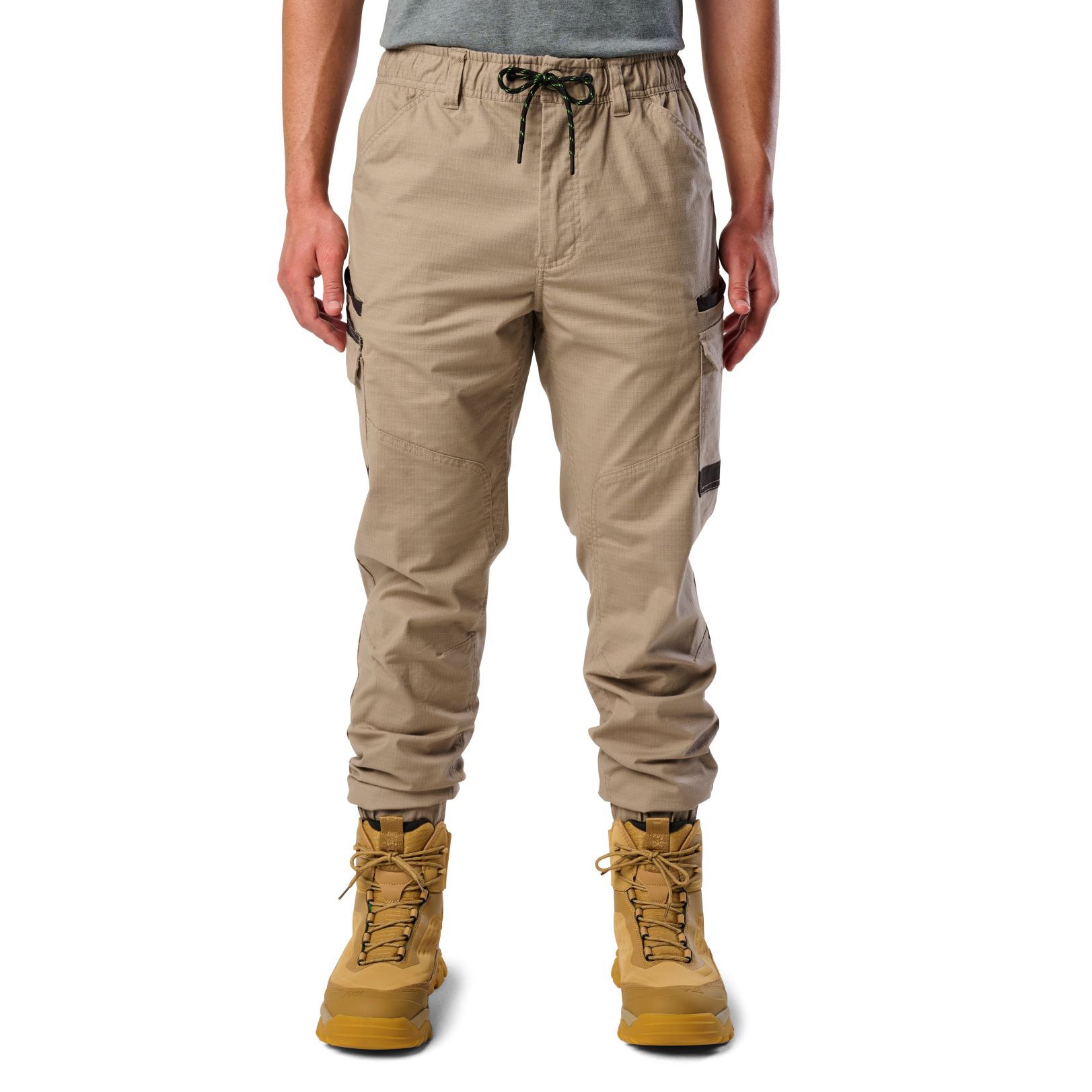 A man wearing khaki cargo style FXD WP-12C Elastic Waist Stretch Ripstop Cuffed Work Pants (FX02506027) with a drawstring waist and wheat work boots, shown from the waist down on a plain white studio background.
