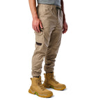 A 3-4 front view of a man wearing khaki cargo style FXD WP-12C Elastic Waist Stretch Ripstop Cuffed Work Pants (FX02506027) with a drawstring waist and wheat work boots, shown from the waist down on a plain white studio background.