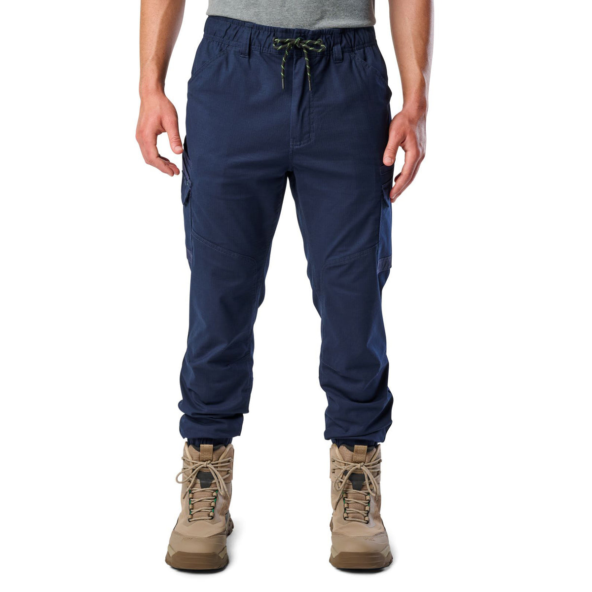 A front view of a man wearing navy cargo style FXD WP-12C Elastic Waist Stretch Ripstop Cuffed Work Pants (FX02506027) with a drawstring waist and stone work boots, shown from the waist down on a plain white studio background.
