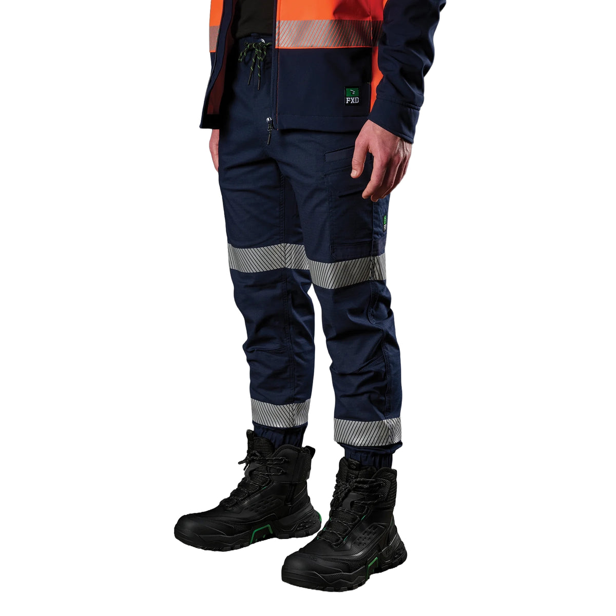 A 3-4 view of a man wearing navy FXD Men's WP-12CT Elastic Waist Stretch Ripstop Cuffed Taped Work Pants (FX02606029) with reflective tape at the knees and cuffs, paired with a matching navy and orange high-vis jacket and black boots, on a white background.