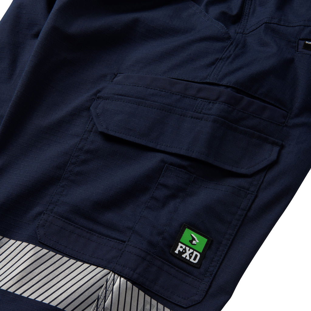 A close up flat lay showing the pocket and tape detail on a pair of navy FXD Men's WP-12CT Elastic Waist Stretch Ripstop Cuffed Taped Work Pants (FX02606029) on a white background.