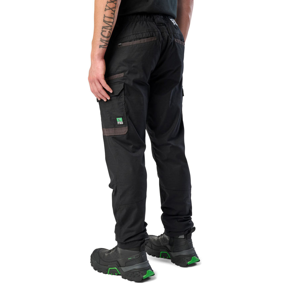 A 3-4 back view of a man wearing black cargo style FXD Men's WP-12 Elastic Waist Stretch Ripstop Work Pants (FX02506026) with black work boots on a white background.