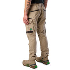 A 3-4 back view of a man wearing khaki cargo style FXD Men's WP-12 Elastic Waist Stretch Ripstop Work Pants (FX02506026) with stone coloured work boots on a white background.