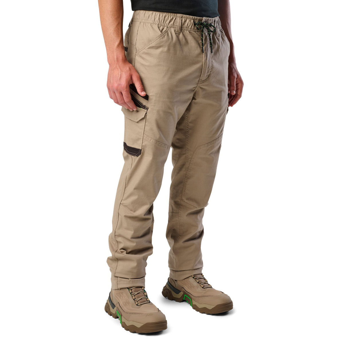 A 3-4 front view of a man wearing khaki cargo style FXD Men's WP-12 Elastic Waist Stretch Ripstop Work Pants (FX02506026) with stone coloured work boots on a white background.