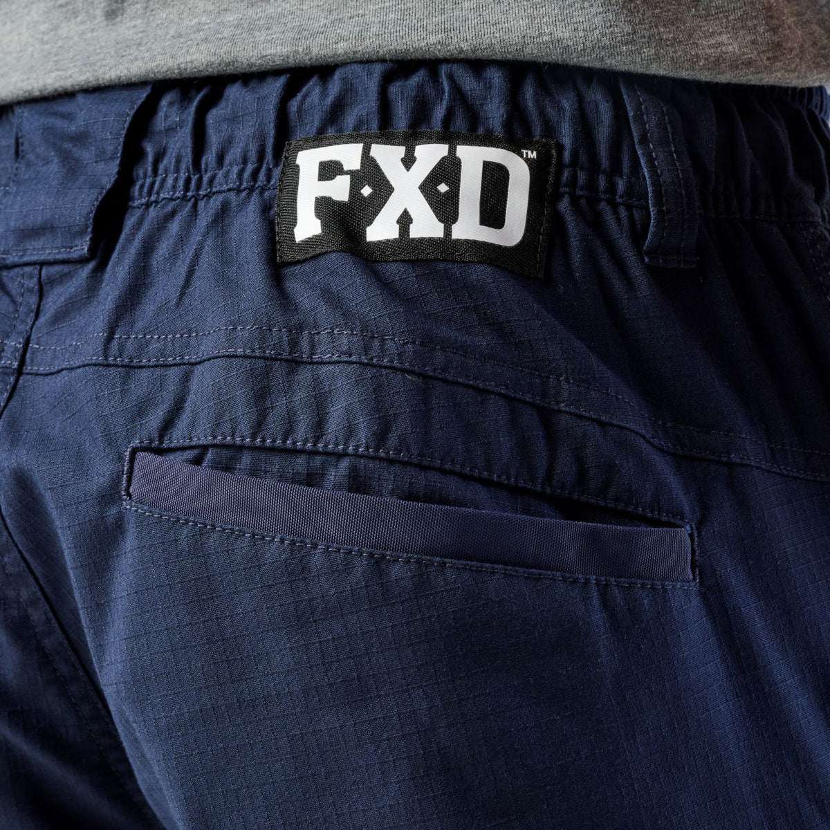 A close up of the back waist on a pair of navy blue cargo style FXD Men's WP-12 Elastic Waist Stretch Ripstop Work Pants (FX02506026) on a white background.