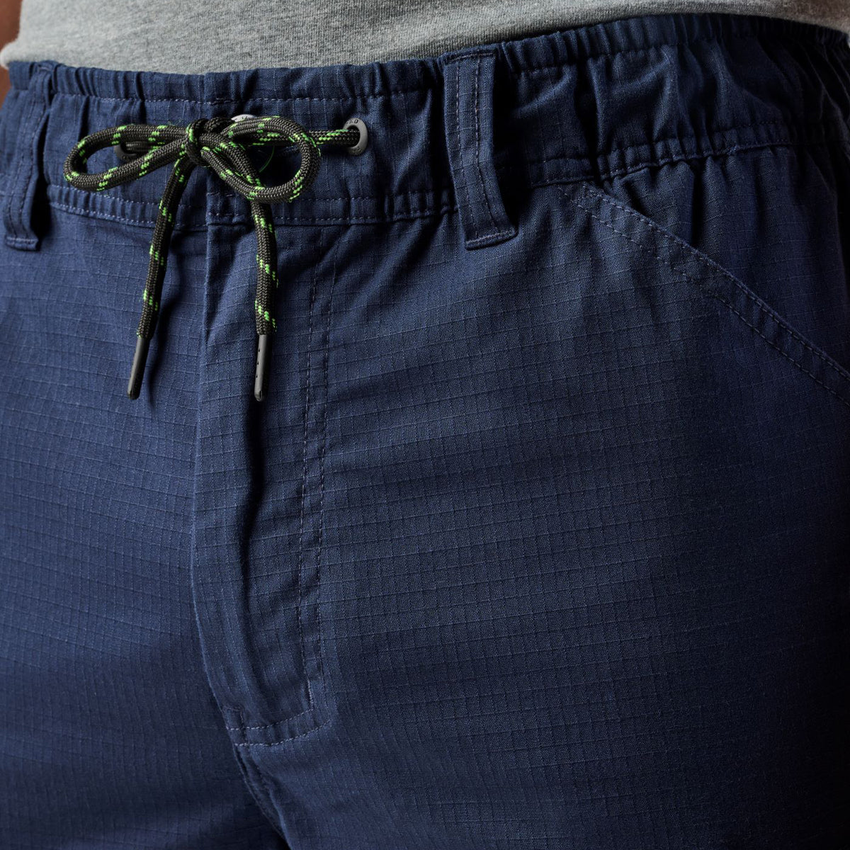 Close up waist detail of a pair of navy blue cargo style FXD Men's WP-12 Elastic Waist Stretch Ripstop Work Pants (FX02506026) on a white background.