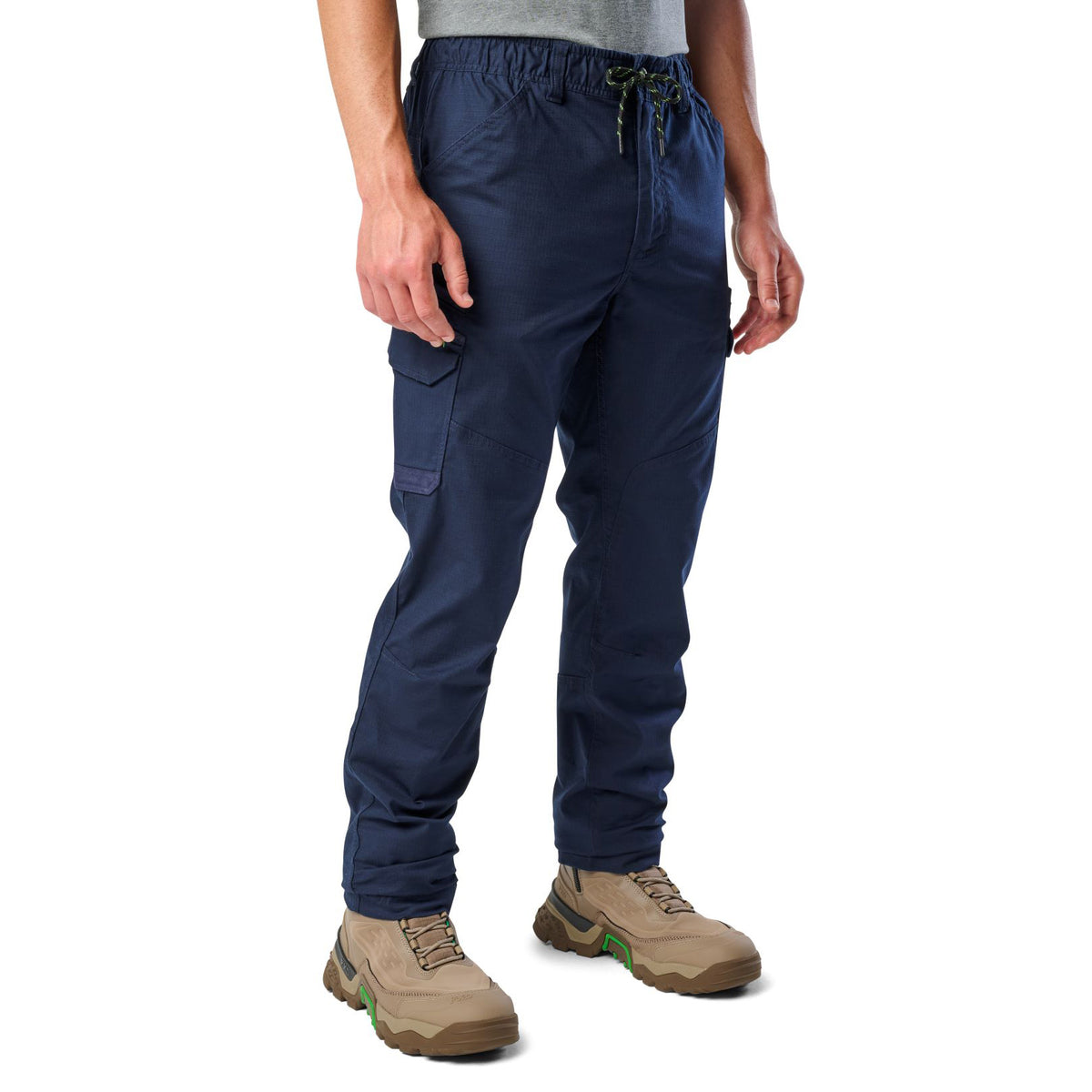 A 3-4 front view of a man wearing navy blue cargo style FXD Men's WP-12 Elastic Waist Stretch Ripstop Work Pants (FX02506026) with stone coloured work boots on a white background.