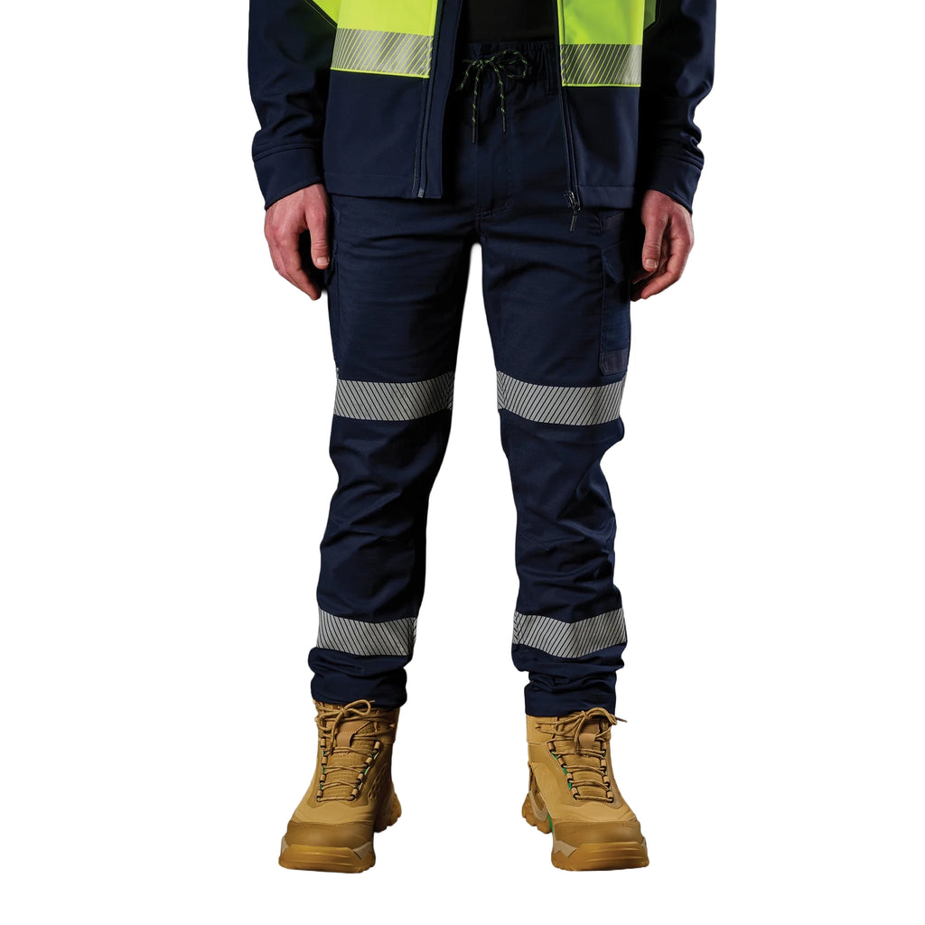 A man wearing a pair of navy blue FXD Men's WP-12T Elastic Waist Stretch Ripstop Taped Work Pants (FX02606028) with a hi vis jacket and wheat coloured work boots, on a white background.