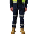A man wearing a pair of navy blue FXD Men's WP-12T Elastic Waist Stretch Ripstop Taped Work Pants (FX02606028) with a hi vis jacket and wheat coloured work boots, on a white background.