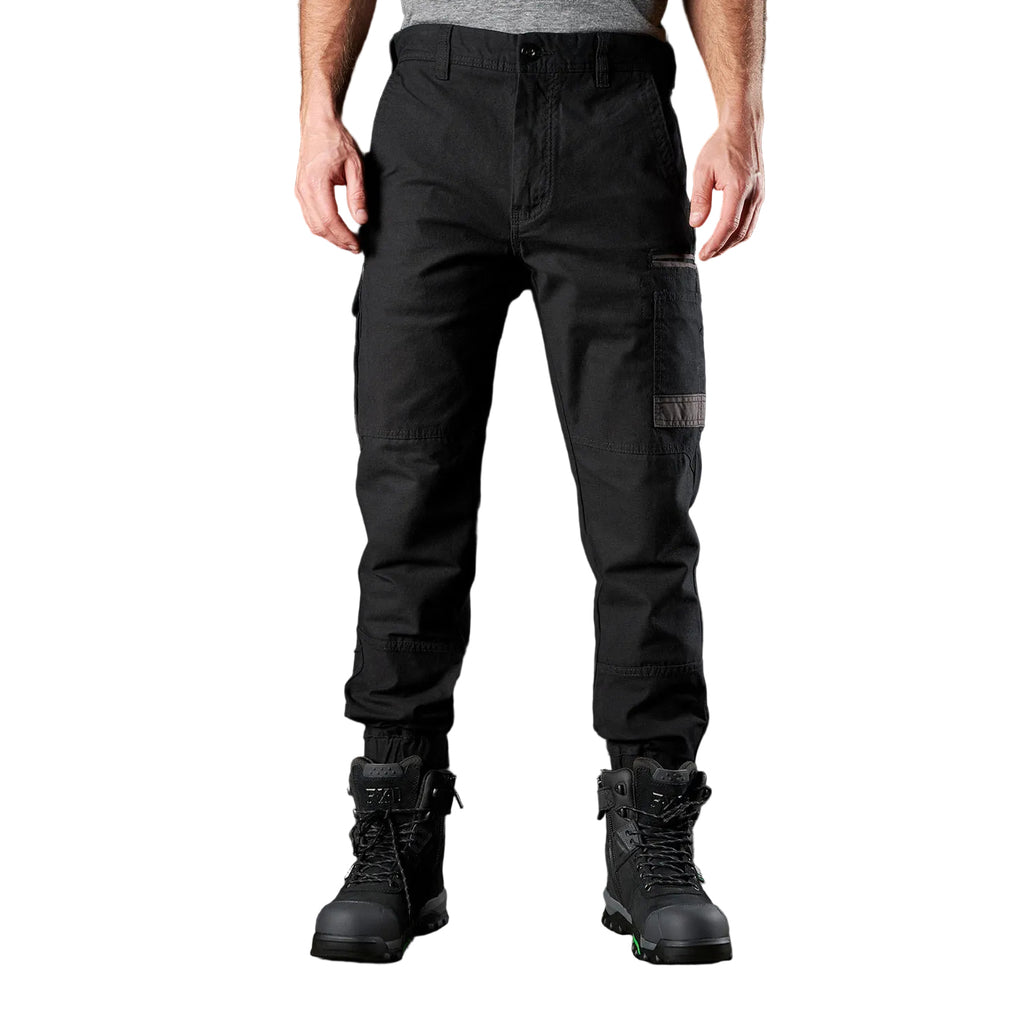 A man wearing black FXD Men's WP-4 Stretch Cuffed Work Pants (FX01616003) with cargo pockets and elastic cuffed ankles, paired with black work boots, shown against a plain white background.