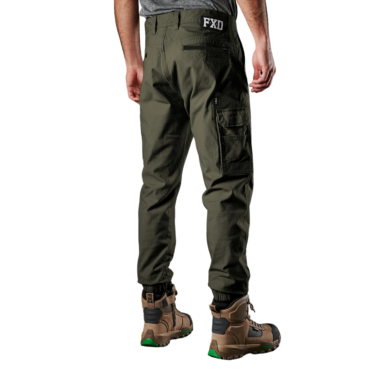 A man viewed from behind wearing green FXD Men's WP-4 Stretch Cuffed Work Pants (FX01616003) with cargo pockets and elastic cuffed ankles, paired with wheat coloured work boots, shown against a plain white background.