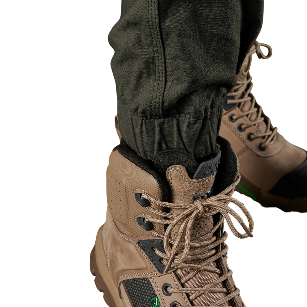 Close up cuff detail on a pair of green FXD Men's WP-4 Stretch Cuffed Work Pants (FX01616003) paired with wheat coloured work boots shown against a plain white background.