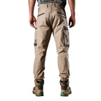 A back view of a man wearing khaki FXD Men's WP-4 Stretch Cuffed Work Pants (FX01616003) with cargo pockets and elastic cuffed ankles, paired with wheat coloured work boots, shown against a plain white background.
