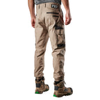 A 3-4 back view of a man wearing khaki FXD Men's WP-4 Stretch Cuffed Work Pants (FX01616003) with cargo pockets and elastic cuffed ankles, paired with wheat coloured work boots, shown against a plain white background.