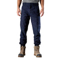 A man wearing navy FXD Men's WP-4 Stretch Cuffed Work Pants (FX01616003) with cargo pockets and elastic cuffed ankles, paired with wheat coloured work boots, shown against a plain white background.