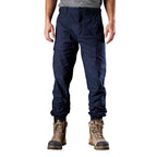 A man wearing navy FXD Men's WP-4 Stretch Cuffed Work Pants (FX01616003) with cargo pockets and elastic cuffed ankles, paired with wheat coloured work boots, shown against a plain white background.